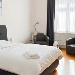 Helles Schlafzimmer im Apartment Derendorf 3 – Komfortbett und Sitzbereich mit Tageslicht in Duesseldorf